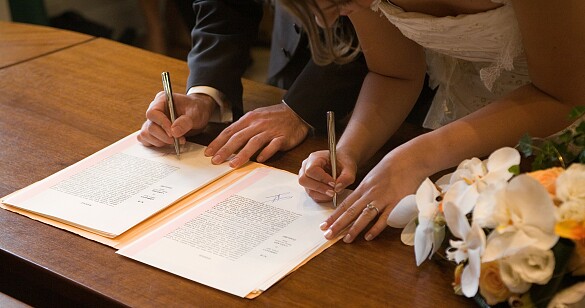Ein Ehepaar unterschreibt eine Urkunde bei einer Hochzeit.