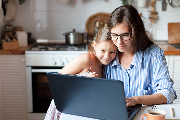 Eine Mutter sitzt mit ihrer Tochter vor einem Laptop