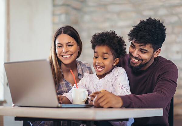 Eine Familie sitzt an einem Tisch, vor ihnen ein Laptop.