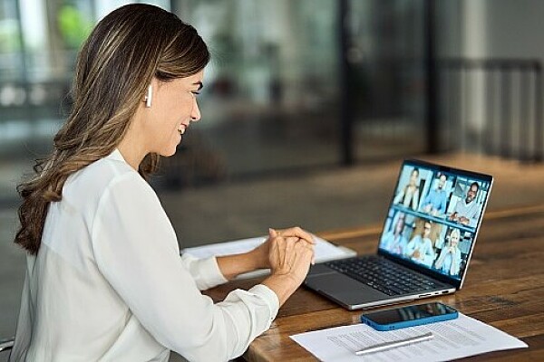 Frau sitzt vor einem Laptop und nimmt an einer Videokonferenz teil