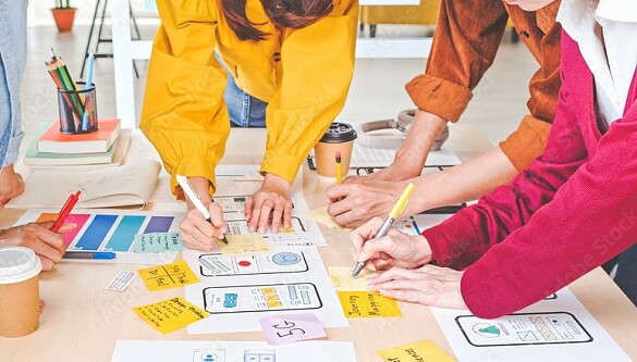 Fünf Personen arbeiten zusammen an einem Tisch.