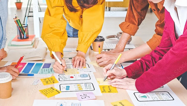 Fünf Personen arbeiten zusammen an einem Tisch.